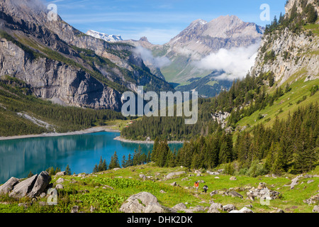 Un homme et une femme la randonnée au-dessus du lac Oeschinen, Alp, Unterbaergli à vue, Wildstrubel Oberland Bernois, Canton de Berne, Switzerl Banque D'Images