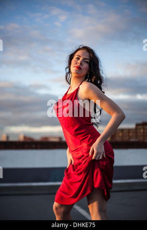 Portrait d'une femme debout, en randonnée jusqu'à sa robe rouge, Londres, Angleterre, Royaume-Uni. Banque D'Images