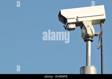 Low angle view of a white CCTV monté contre un ciel bleu clair. Banque D'Images