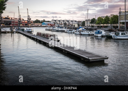 Yachts, grues et plaisir cruiser amarré au ponton flottant dans le port de plaisance de quais de Bristol, Avon, Angleterre au coucher du soleil. Banque D'Images