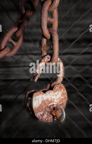 Big old rusty metal cadenas ouvert avec une clé accrochée à un chaîne de caractères gras Banque D'Images