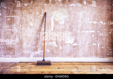 Une brosse en bois (genêt) appuyé contre un mur de plâtre de gypse (dénudé) au cours de la décoration rénovation d'amélioration Banque D'Images