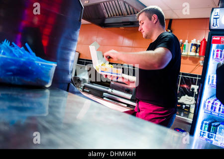 Un homme travaillant dans un poisson et chip shop, UK Banque D'Images