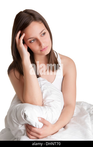 Femme assise sur un lit, se réveillant, isolé en blanc Banque D'Images