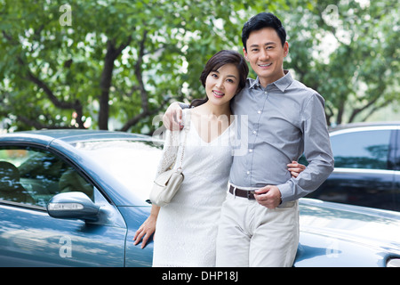 Heureux couple appuyé contre une nouvelle voiture Banque D'Images