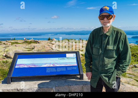 Un homme Senior citizen, un vétéran de l'armée américaine, se trouve à côté d'un panneau d'information pour Cadillac Mountain dans l'Acadia National Park Banque D'Images