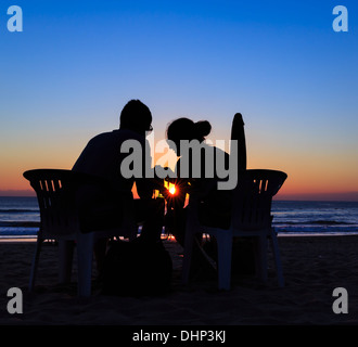 Un couple assis sur la plage au coucher du soleil, de la plage de Sanur, Bali, Indonésie Banque D'Images