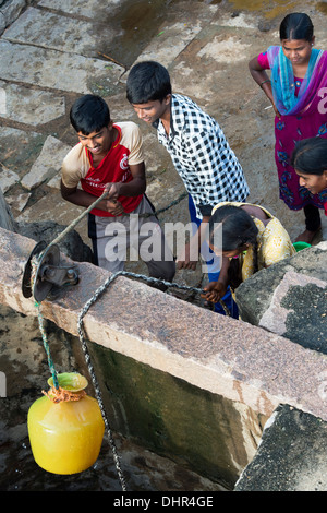 Les filles et les garçons adolescents indiens dimensions de l'eau d'un puits dans un village-rue de l'Inde rurale. L'Andhra Pradesh, Inde Banque D'Images