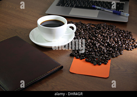 Photo focus White Coffee cup et l'ordinateur sur une table en bois et feuilles de carnet coincé. Banque D'Images