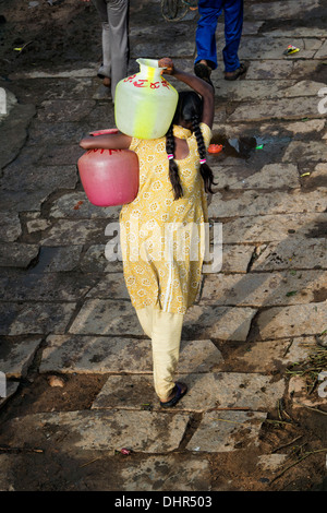 Indian girl portant de l'eau loin des pots d'un puits dans un village-rue de l'Inde rurale. L'Andhra Pradesh, Inde Banque D'Images