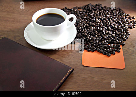 Photo focus White Coffee cup et l'ordinateur sur une table en bois et feuilles de carnet coincé. Banque D'Images