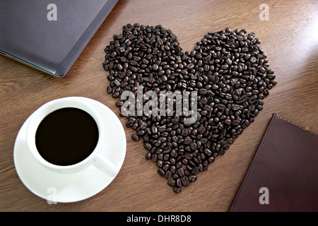 Le concept de la tête en forme de grains de café disposées en un cœur près de white tasse à café. Banque D'Images