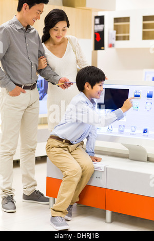 Garçon agréable de toucher l'écran de l'ordinateur avec les parents à côté Banque D'Images