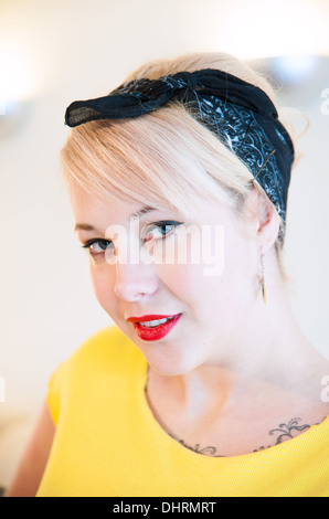 Jeune femme blonde wearing vintage 1950s style headband looking at camera smiling Banque D'Images