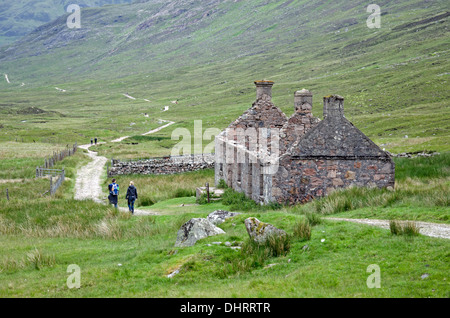 Les randonneurs passent par une ruine croft sur une rive de la West Highland Way entre Kinlochleven et Fort William. Banque D'Images