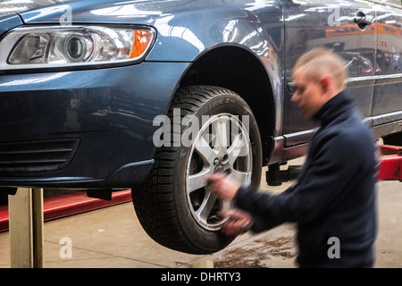 Mécanicien automobile changer les pneus d'été et le montage des pneus d'hiver sur roues du véhicule sur la rampe d'accès à l'atelier de montage de pneu Banque D'Images