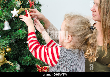 Petite fille et sa mère la décoration de l'arbre de Noël Banque D'Images