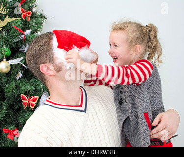 Père et fille s'amusant à la Noël. Fille essaie de mettre sur Santa's hat le père. Banque D'Images