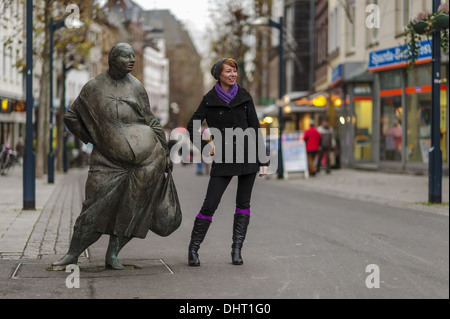 Jeune femme et statue en bronze dans une rue Banque D'Images