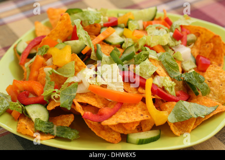 Tas de nachos avec légumes sur plaque verte. Banque D'Images