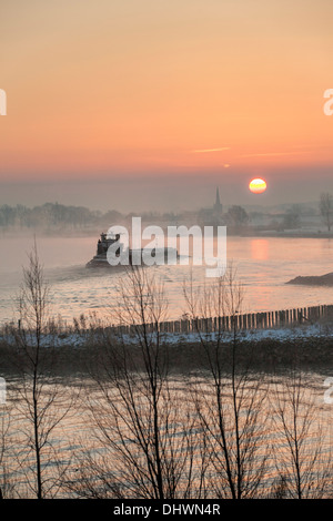 Pays-bas, Lopik, toits de village près de la rivière Lek. Inland barge cargo. Le lever du soleil. L'hiver Banque D'Images