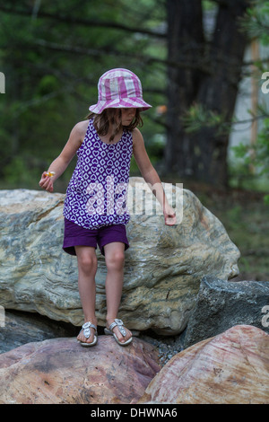 Parution modèle jeune fille souriante, à l'extérieur, profiter de la nature et de marcher sur de grosses roches. Banque D'Images
