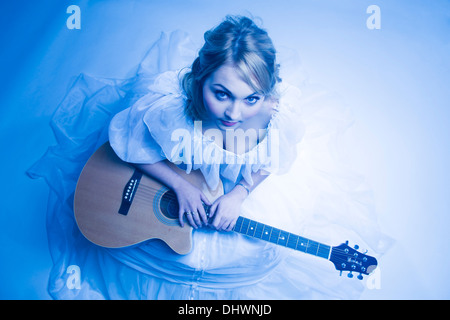 Vue aérienne d'une jeune femme blonde adolescente dans un conte de fées dress blanc avec une guitare Banque D'Images