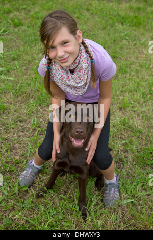 Petite fille embrassant son chien ami sur un pré Banque D'Images