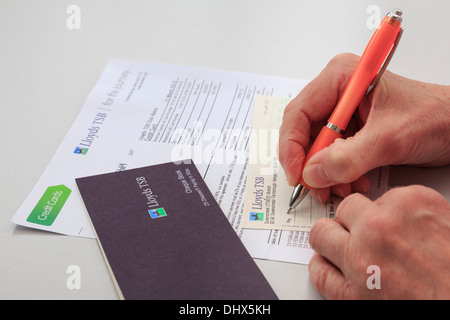 L'écriture d'un pensionné Senior woman Lloyds TSB Bank chèque pour payer une grande carte de crédit. Pays de Galles, Royaume-Uni, Angleterre Banque D'Images