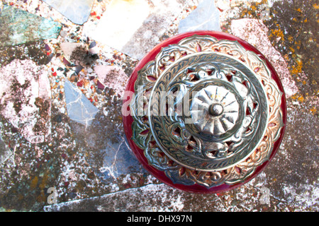 Close up résumé vue aérienne de l'argent et cerise Bol avec couvercle sur table béton et mosaïque Banque D'Images