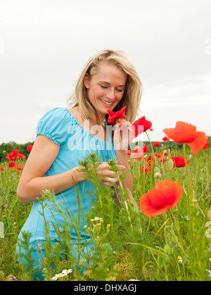 Très belle jeune femme blonde qui sent un coquelicot Banque D'Images