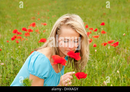 Très belle jeune femme blonde qui sent un coquelicot Banque D'Images