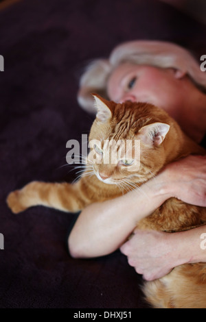 Une femme tenant un chat tigré jaune. Banque D'Images