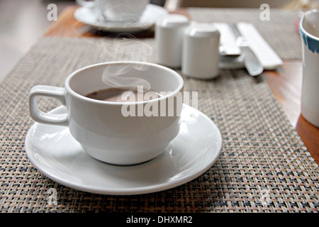 La photo sex café noir dans une tasse blanche sur la table et ont la fumée sortir. Banque D'Images