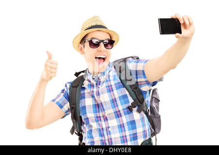 Sac à dos avec l'homme de prendre des photos de lui-même avec un téléphone mobile et giving thumb up Banque D'Images