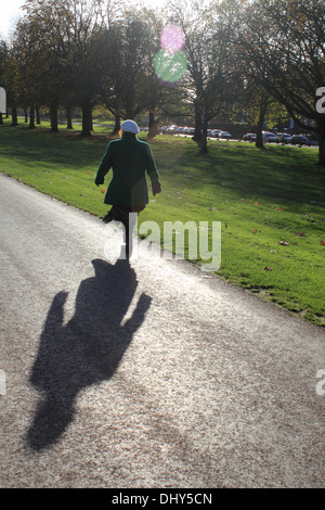 Femme marche dans le soleil d'automne sur la Longue Marche, Windsor, Berkshire, Royaume-Uni. Banque D'Images