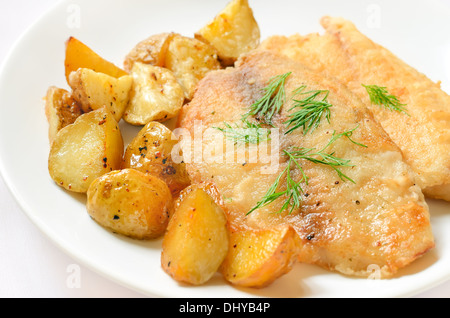 Filet de poisson frit avec des pommes de terre au four sur plaque blanche Banque D'Images