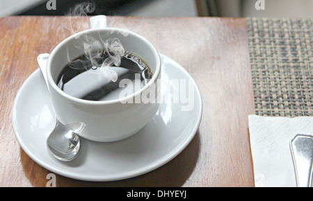 La photo sex café noir dans une tasse blanche sur la table et ont la fumée sortir. Banque D'Images