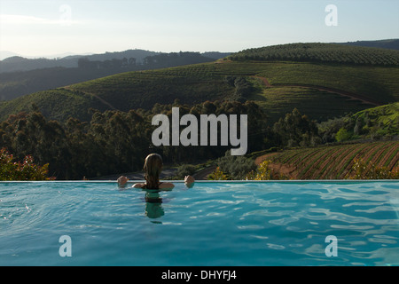 Une femme jouit de la vue sur les vignobles de Stellenbosch, une piscine à débordement en Afrique du Sud. Banque D'Images