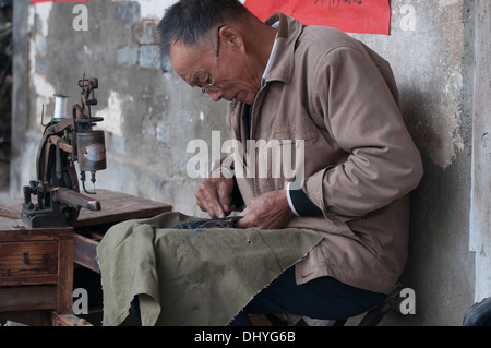 Réparateur de chaussures à l'œuvre dans l'heritage village de Tangmo, Huizhou, Anhui, Chine Banque D'Images