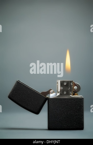 Briquet à essence noir avec flamme sur fond sombre Banque D'Images