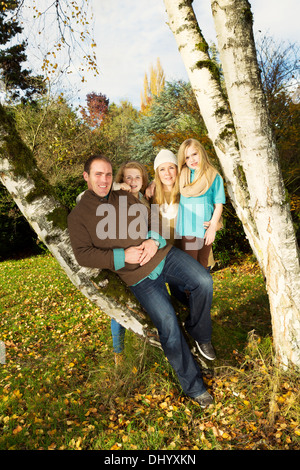 Photo de famille verticale reposant sur les arbres, avec l'homme en avant-garde, au cours d'une journée agréable en automne Banque D'Images