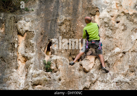 Un homme en face d'un mur de pierre à la recherche de la meilleure route, l'escalade à Mijas, Costa del Sol, Espagne. Banque D'Images