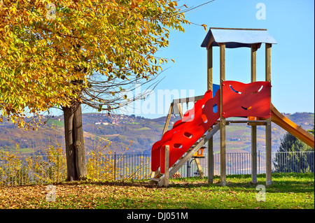 L'enfant solitaire faites glisser sur l'aire vide en automne dans la petite ville de Diano d'Alba, Italie. Banque D'Images