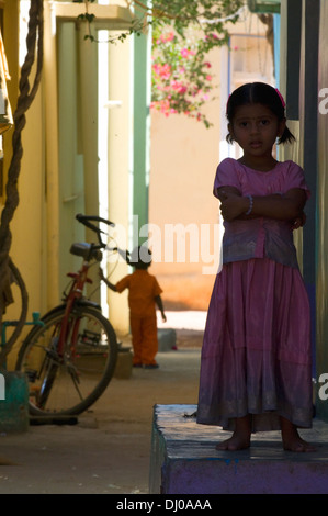 Fille enfant debout sur le seuil de sa maison dans les petites rues de Puttaparthi Bangalore Inde du Sud Banque D'Images