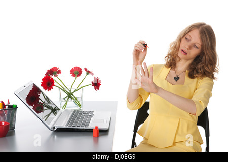 Jeune femme isbringing vernis derrière son bureau Banque D'Images