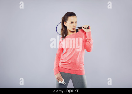 Jolie fit woman holding badminton racket regardant copyspace debout sur fond gris Banque D'Images