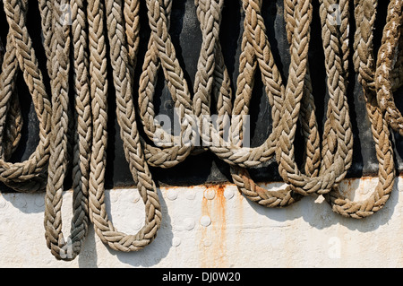 Tall Ship's amarres de lien sur un noir et blanc coque en acier peint. Banque D'Images