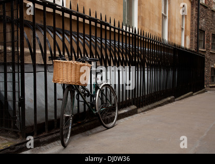 Chers vieux vélo avec panier en osier cadenassée à l'extérieur garde-corps noir bureaux du centre-ville Banque D'Images