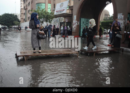 Gaza, Territoires Palestiniens, . 18 nov., 2013. Des étudiants palestiniens à pied sur un morceau de métal de l'utiliser comme un pont pour passer l'eau de pluie sur une rue pendant les fortes pluies diluviennes dans la ville de Gaza le 18 novembre 2013.Photo : Ahmed Deeb/NurPhoto Crédit : Ahmed Deeb/NurPhoto ZUMAPRESS.com/Alamy/Live News Banque D'Images